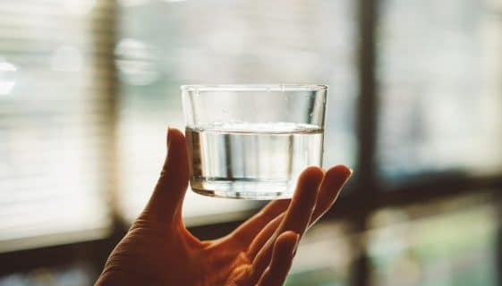 Glass Of Spring Water Being Held By Hand — Spring Water Online in Agnes Water, QLD