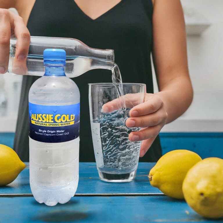 Woman Pouring Water on Glass with Lemons on Side