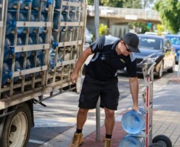 Man Bending To Reach A Gallon Of Spring Water — Spring Water Online in Tieri, QLD