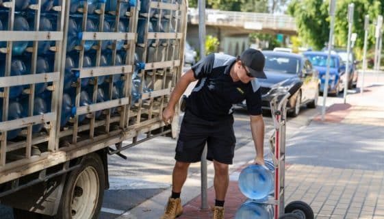Man Bending To Reach A Gallon Of Spring Water — Spring Water Online in Tieri, QLD