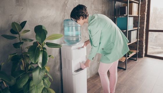 Woman Refilling Glass of Water — Spring Water Online in Mackay, QLD Woman Refilling Glass of Water — Spring Water Online in Mackay, QLD