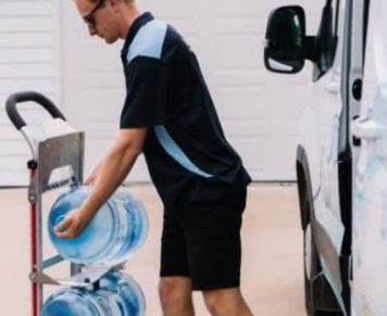 Man Placing A Gallon Of Spring Water On A Wheel Cart — Spring Water Online in Middlemount, QLD