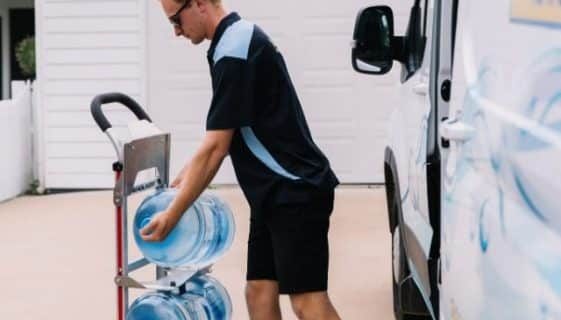 Man Placing A Gallon Of Spring Water On A Wheel Cart — Spring Water Online in Middlemount, QLD