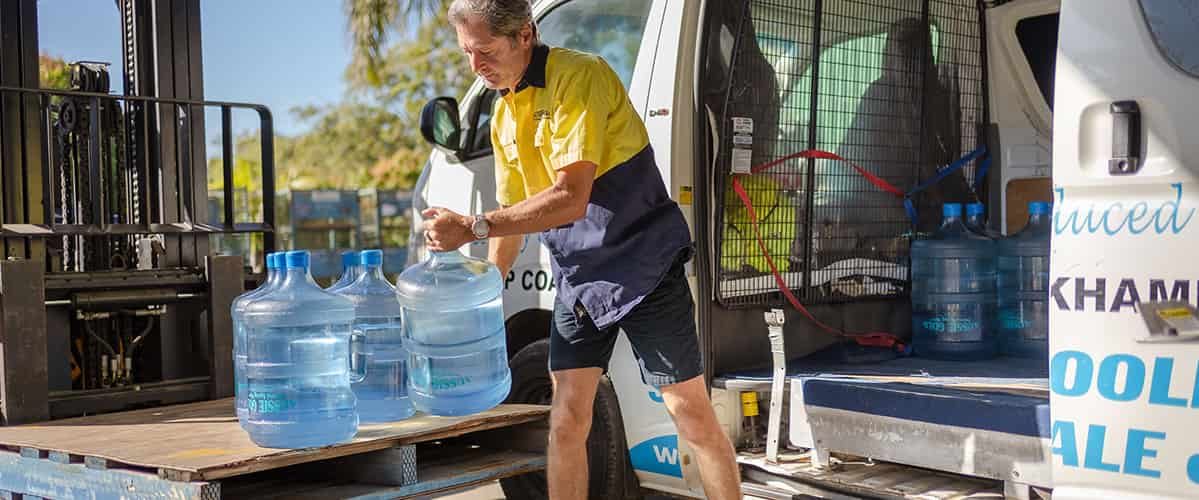 Man lifting bottle of waters to the van — Spring Water Supplier in Yeppoon, QLD