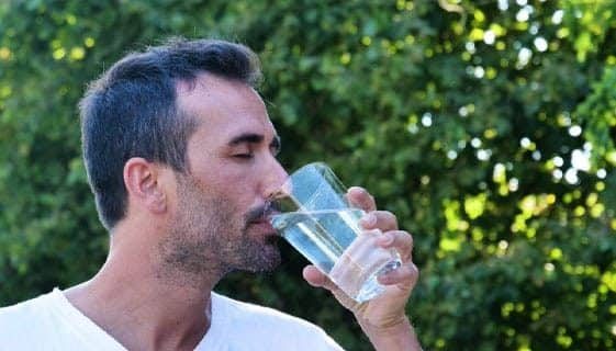Man Drinking Water Outside His Home — Spring Water Online in Clermont, QLD