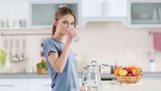 Young Woman Drinking Water In Their Kitchen